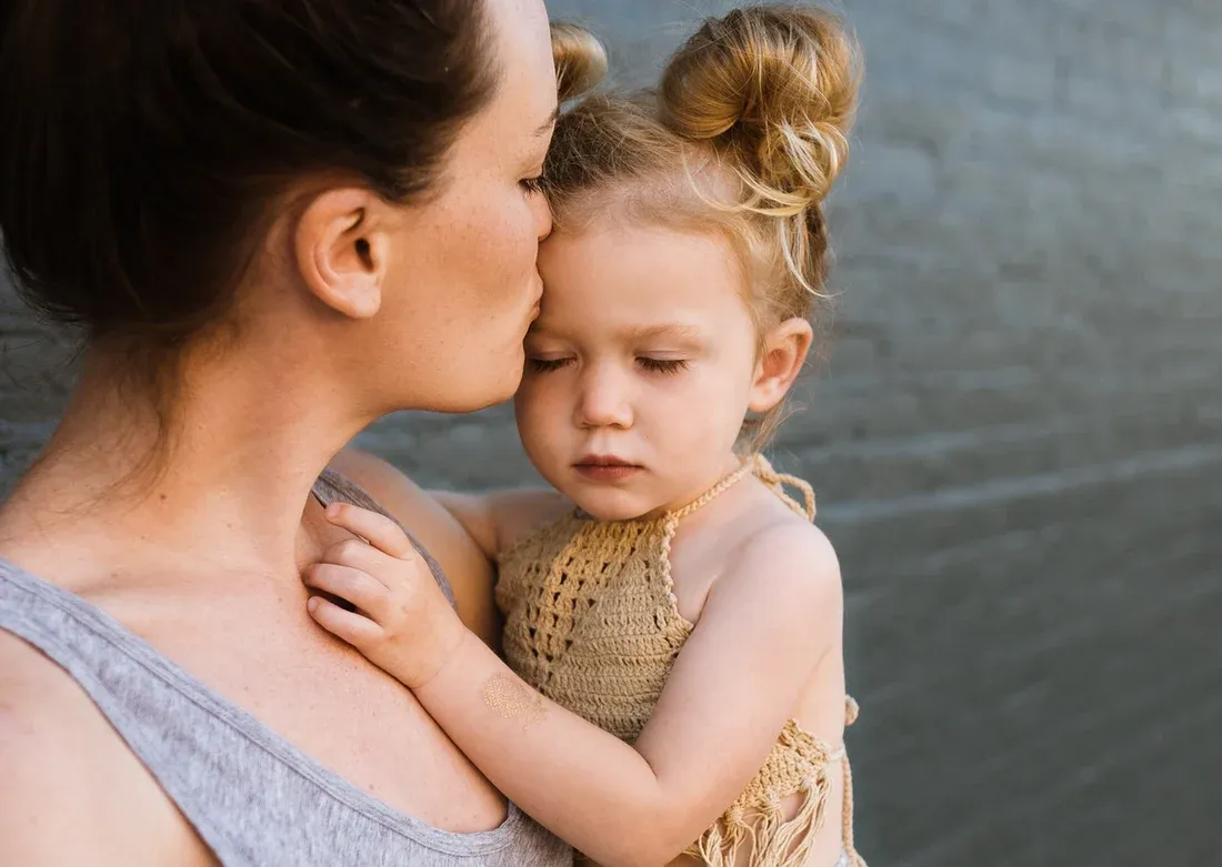 A mother holding her toddler suffering from Sore throat