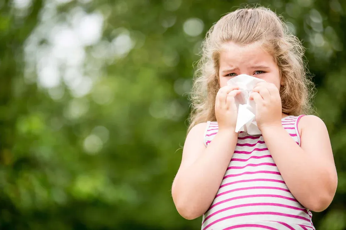 A young girl blowing her nose